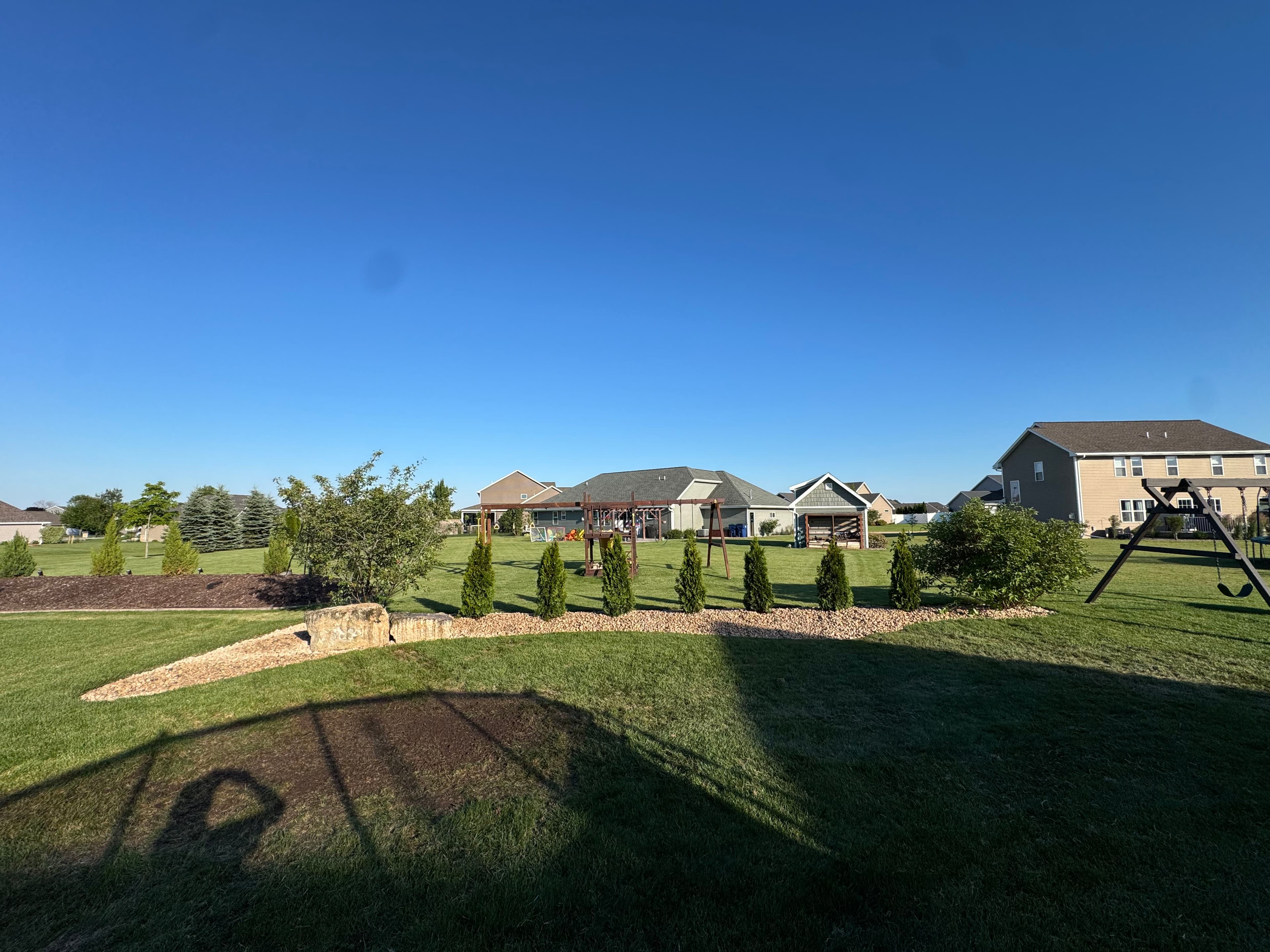 Project Rock Beds and Arborvitaes Replace Worn Mulch in This Backyard image