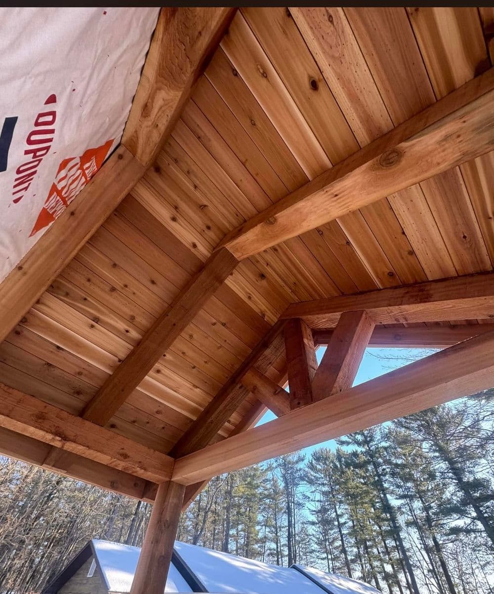 Close-up view of a wooden arch ceiling with exposed beams in a rustic outdoor setting.